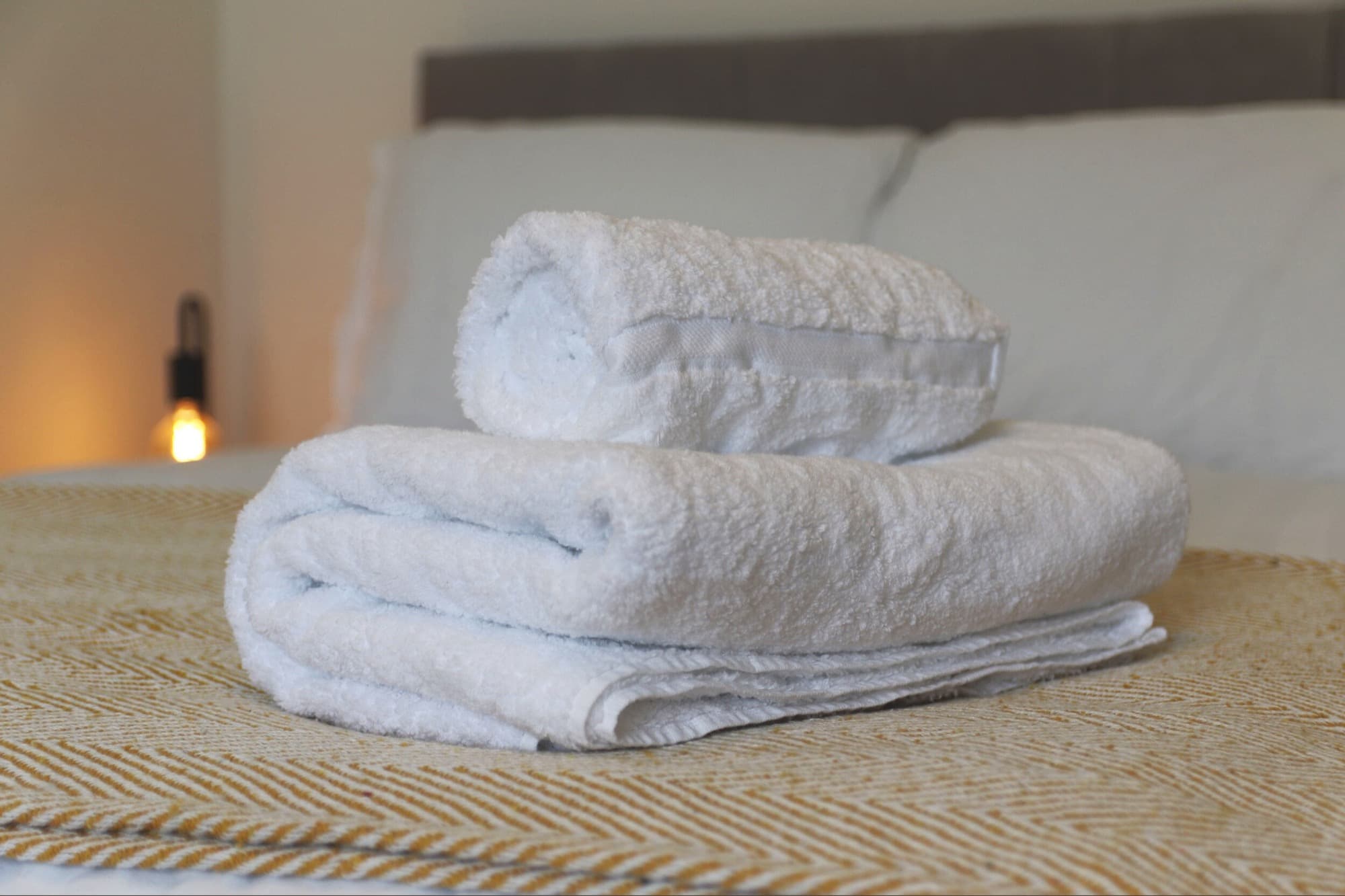 Fresh white towels styled on a short-let bedroom bed in Nottinghamshire