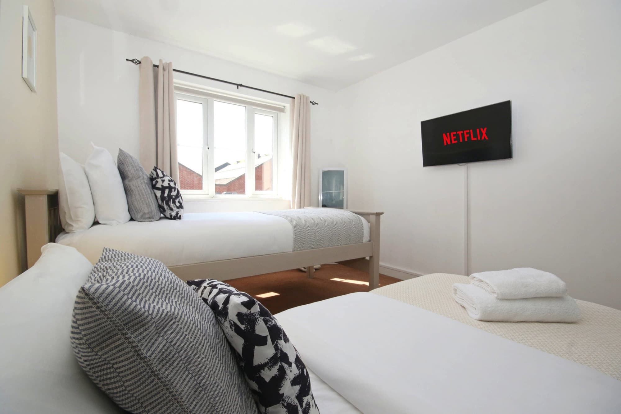 Bright twin bedroom with soft furnishings and warm lighting in a managed short-let