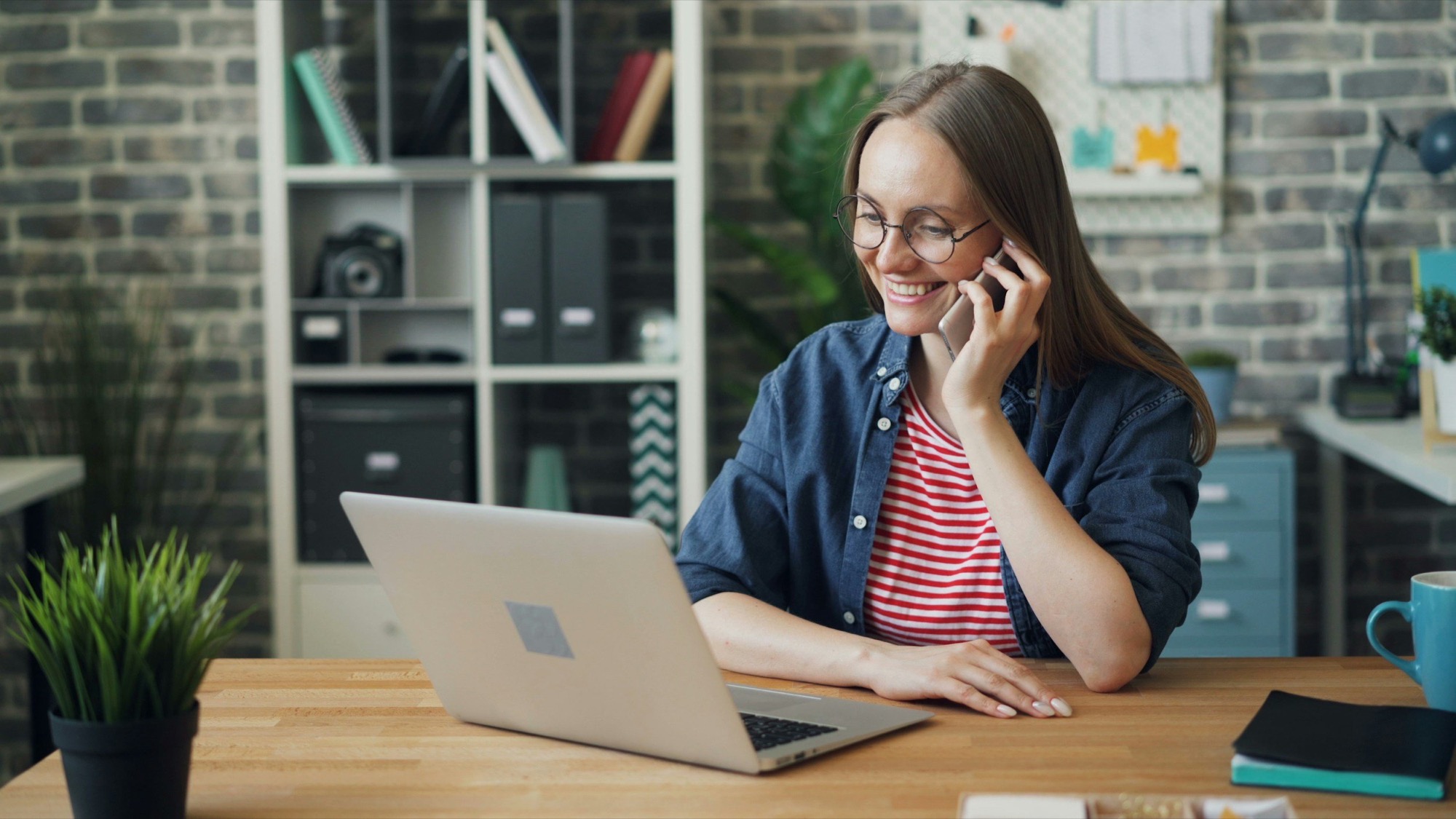 Airbnb manager on the phone to a guest while working at a laptop